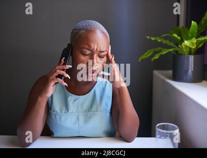 Una giovane donna d'affari nera tiene la testa mentre è in attesa di una chiamata stressante Foto Stock