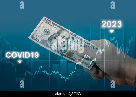 inflazione nel 2022 e nel 2023. l’uomo detiene un conto del cento dollari contro il grafico dei tassi di inflazione in aumento. iperinflazione del dollaro al buio Foto Stock