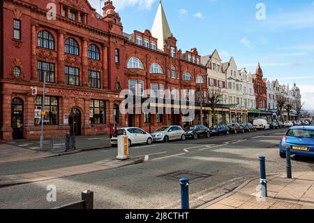 L'imponente facciata in mattoni rossi e terracotta dell'Ufficio postale di Llandudno e della Galleria d'Arte in una strada piena di negozi al dettaglio e fiancheggiata da auto parcheggiate Foto Stock