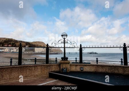 Inizio 20th secolo cemento ferro e pietra Llandudno bandstand con una parete posteriore semicircolare al podio arredato con una lampada in ferro su un molo Foto Stock