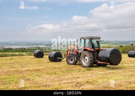 Ballymacwilliam, West Cork, Irlanda. 15th maggio 2022. Le temperature hanno raggiunto i 20C a West Cork oggi, il che ha permesso agli agricoltori di terminare il loro primo taglio di insilato per l’anno. I contraenti di o'Donovan hanno salvato l'insilato per il coltivatore di latte, Noel o'Donovan. Credit: AG News/Alamy Live News. Foto Stock