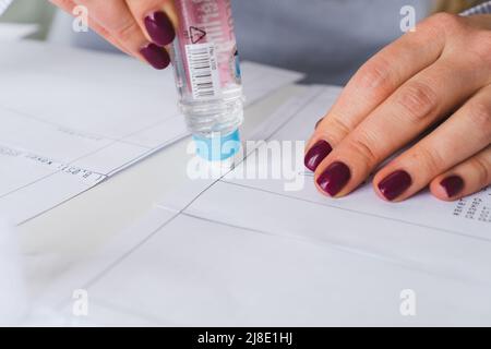 Donna su misura durante il lavoro su modelli di cucitura. Unire i dettagli della carta per vestire Foto Stock