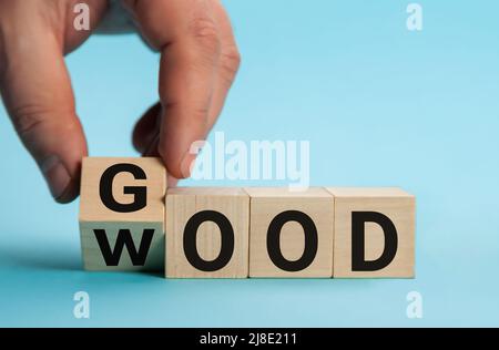 Parola buono a legno. Mano sta girando un dado e cambia la parola buono a legno. Foto Stock