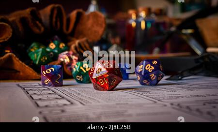 Primo piano di versamento di dadi di diversi tipi da un sacchetto di dadi su un foglio di carattere. Foto Stock