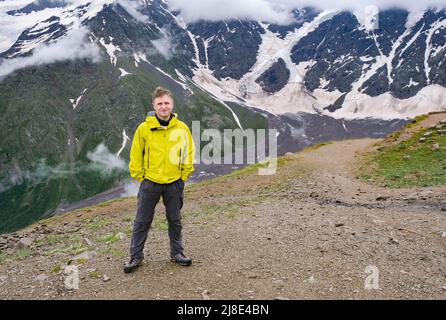 Giovane uomo in giacca gialla con vista sulle montagne. Foto Stock