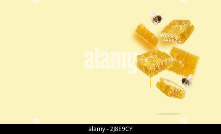 Pezzi volanti di nido d'ape, goccia di miele e api su sfondo giallo. Una composizione concettuale di favi galleggianti. Cibo sano Foto Stock