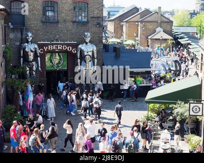 Ammira i turisti e gli amanti dello shopping che camminano intorno all'affollato mercato di Camden a Londra Foto Stock