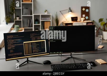 Immagine di sfondo di due computer sul luogo di lavoro con righe di codice sullo schermo in ufficio sviluppatori IT, spazio di copia Foto Stock