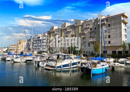 Splendida vista sul molo con barche, yacht e un alto edificio sulle rive del pittoresco canale mediterraneo nel Golf de Roses ancora una volta Foto Stock