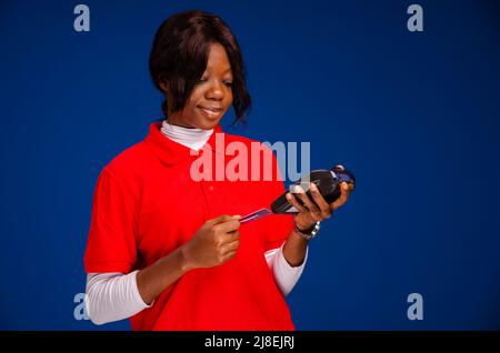 donna africana che mette una carta di credito in un dispositivo del punto vendita Foto Stock