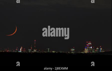 Il fotografo del Regno Unito, che si chiama Dusty Lens UK, ha catturato queste splendide foto di una luna crescente dietro lo skyline di Londra il 14th aprile 2021. L'immagine è presa da una enorme 23 miglia di distanza nella campagna del Kent. La luna appare di colore arancione e rosso a causa delle atmosfere e dell'inquinamento atmosferico. Le sue grandi dimensioni sono dovute alla tecnica di compressione dell'obiettivo. Dusty ha detto ‘’si può vedere l'occhio di Londra e l'arco di Wembley illuminato. L'iconico grattacielo Shard di Londra e anche la cupola della Cattedrale di St. Pauls. La banca nuvola era estesa ma sapevo che era chiaro in lontananza, quindi i j Foto Stock