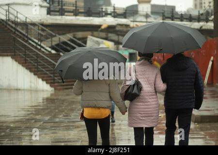Famiglia sotto la pioggia. Persone con ombrelloni in strada. Passeggia per la città con il tempo piovoso. La gente a Mosca in autunno. Foto Stock