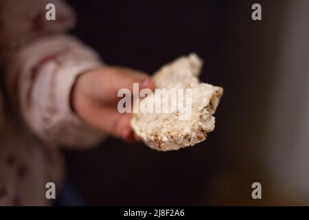 Pane di cereali in mano del bambino. Colazione sana. Il preschooler contiene la pagnotta di grani bianchi. Pezzare il pezzo di pane secco. Foto Stock