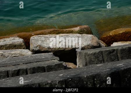 rocce parzialmente sommerse con alghe lungo il lungolago Foto Stock