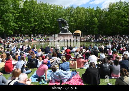 Varsavia, Polonia. 15th maggio 2022. Le persone si siedono sull'erba e si godono la musica di Frederic Chopin eseguita da un pianista durante un concerto all'aperto al Royal Lazienki Park di Varsavia, Polonia, 15 maggio 2022. Domenica è iniziata la stagione 63rd dei Concerti Chopin nella Lazienki reale. I recital ai piedi del monumento Chopin si tengono ogni domenica dal 15 maggio al 25 settembre. Credit: Alexey Vitvitsky/Xinhua/Alamy Live News Foto Stock