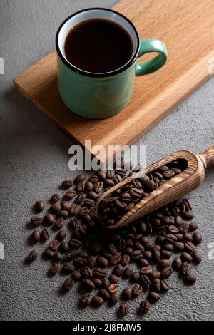 Tazza di caffè verde con chicchi di caffè su sfondo di cemento Foto Stock