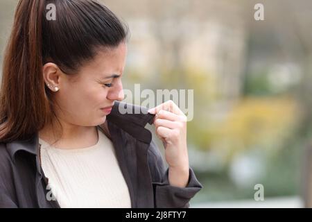 Donna che si lamenta dei vestiti cattivo odore in strada Foto Stock