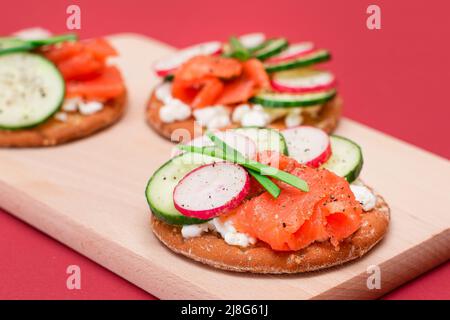 Sandwich Cracker croccanti con salmone fresco, cetriolo, piatto di pesce, formaggio Cottage e cipolle verdi. Colazione facile. Panini veloci e sani. Croccante con gustoso ripieno. Snack dietetico sano Foto Stock