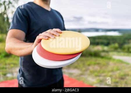 Disc golf player con attrezzatura di frisbee nel campo del parco. Uomo che gioca a discgolf. Torneo sportivo all'aperto. Paesaggio estivo in Finlandia. Foto Stock