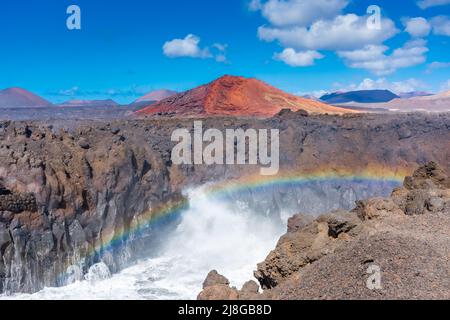 Bellissimo arcobaleno causato dallo schiantamento delle onde dell'Oceano contro le scogliere vulcaniche di Los Hervideros, Lanzarote, Isole Canarie, Spagna Foto Stock