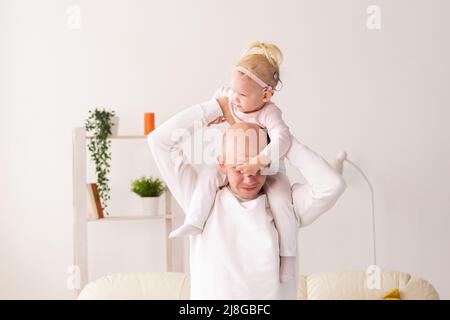 Bambino con impianti cocleari che gioca con suo padre a casa. Sordità e tecnologia medica concetto Foto Stock