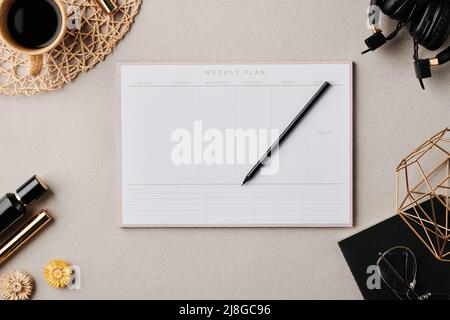 Flatlay di planner con matita circondata da tazza di caffè, copybook nero con occhiali e vasi fatti a mano e altri oggetti Foto Stock