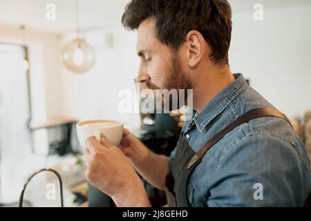 Bel barista con caffè alla moda che puzzava la barba in caffetteria Foto Stock