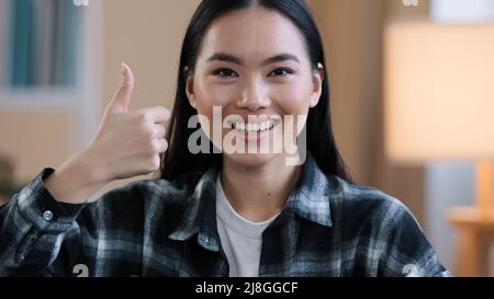 Allegro successo asiatico coreano positivo donna ragazza femmina servizio dentale cliente sorridendo toothy sorriso mostrando pollici in su all'interno in clinica dentista Foto Stock