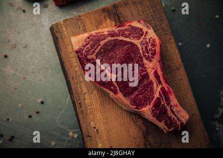 piano tavolo di carne rossa non cotta sulla parte superiore del vecchio tagliere rustico con alcune spolverate di sale e pepe intorno al tavolo di ferro Foto Stock