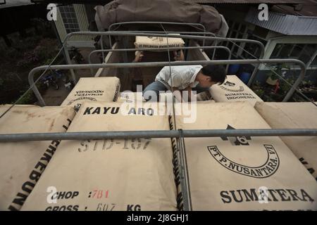 Lavoratori che caricano sacchi di tè su un camion presso la fabbrica di tè Kayu Aro nel villaggio di Kersik Tuo, Kayu Aro, Kerinci, Jambi, Indonesia. Foto Stock