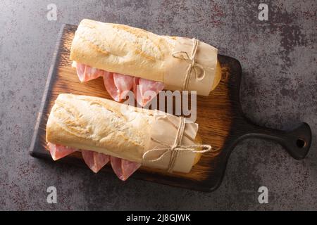 Sandwich francese Jambon-Beurre a base di baguette con burro e prosciutto primo piano sul bordo di legno. Vista dall'alto orizzontale Foto Stock