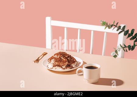 Torta sul piatto con forchetta dorata e tazza di caffè sul tavolo su sfondo rosa Foto Stock