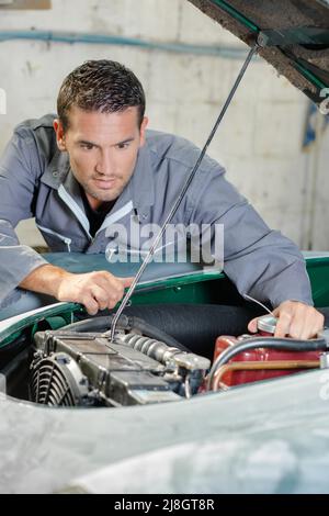 Mechanic guardando auto motore Foto Stock