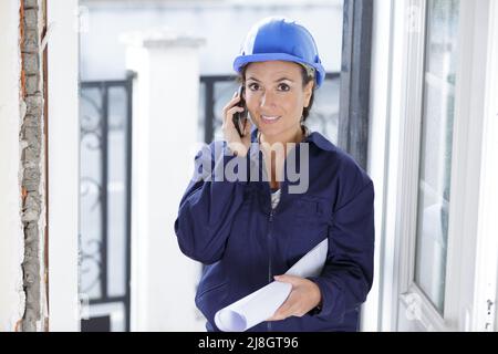 ingegnere donna che indossa il casco utilizzando uno smartphone Foto Stock