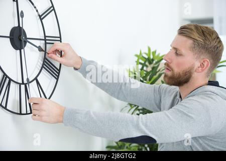 giovane uomo che imposta un grande orologio meccanico Foto Stock