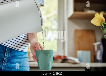 Tempo del tè, Donna versare acqua bollita dal bollitore elettrico in una tazza per preparare il tè, la prima colazione del mattino in cucina Foto Stock