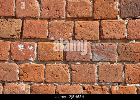 Modello di mattoni rossi. Un vecchio muro di mattoni con crepe e graffi. Un muro con la texture di mattoni rotti. Facciata vintage della casa. Foto Stock