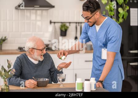 Infermiera a domicilio che dà pillole ad un vecchio Foto Stock