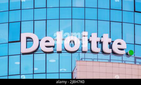 Deloitte segno sulla facciata di vetro di un edificio di uffici Foto Stock