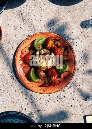 Burrata con pomodori. Insalata alla luce del sole d'estate. Foto Stock