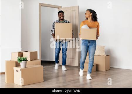Gioiosa coppia afroamericana che trasporta le scatole mobili che entrano nella nuova sede Foto Stock