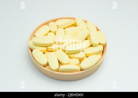 Una pila di compresse di supplemento di calcio e vitamina D isolate su sfondo bianco Foto Stock