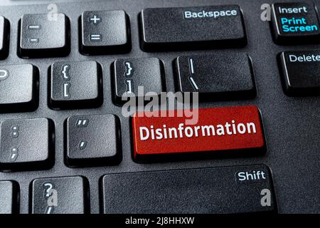 Tasto rosso Disinformation (Disinformazione) sulla tastiera nera del desktop. Messaggio di avvertimento sulla chiave di invio del calcolatore. Propaganda, manipolazione e censura nei media Foto Stock