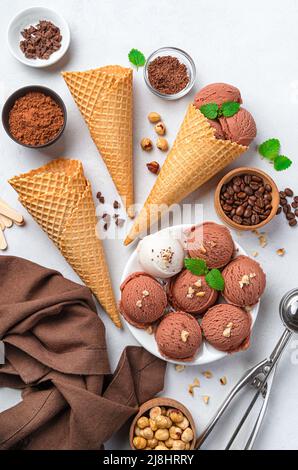 Gelato al cioccolato con vari additivi e cialde su sfondo grigio. Foto Stock