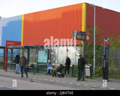 I viaggiatori aspettano una fermata dell'autobus con segni elettronici di itinerari e orari: La politica dei trasporti sostenibile nella città modello di Almere a Flevoland. Foto Stock