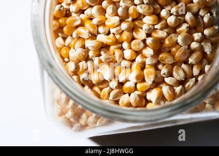 chicchi di popcorn in vaso su bianco Foto Stock