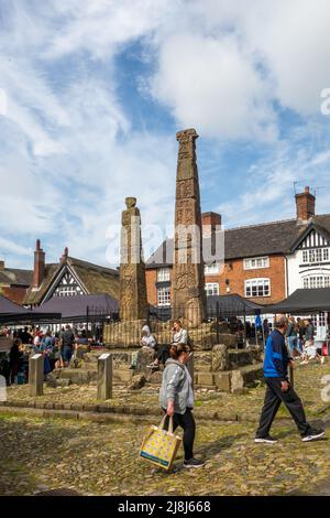 La gente al mercato dei produttori e degli agricoltori intorno alle antiche croci sassoni nella piazza del mercato acciottolato della città di mercato Cheshire di Sandbach Inghilterra Foto Stock