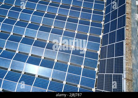 Vista aerea dei pannelli solari fotovoltaici blu montati sul tetto dell'edificio industriale per la produzione di elettricità ecologica verde. Produzione di Foto Stock