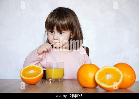 Ritratto di una bambina gioca con un arance su un tavolo. Fuoco selettivo di frutta d'arancia. Stile di vita sano. Foto Stock