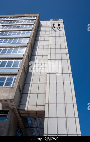 Due persone che si abbischano lungo l'alto edificio principale della torre del Southend University Hospital per beneficenza. Evento di discesa alta. Cielo blu Foto Stock